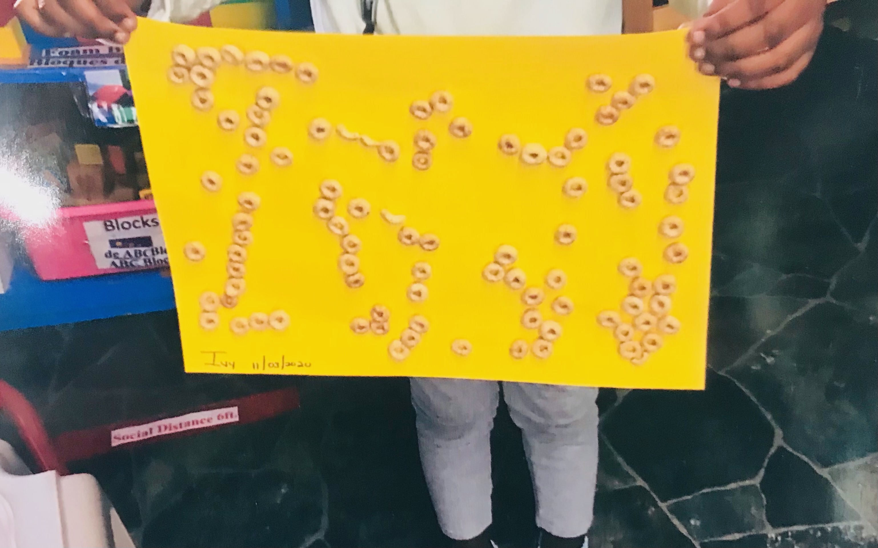 child holding up a cheerio paper